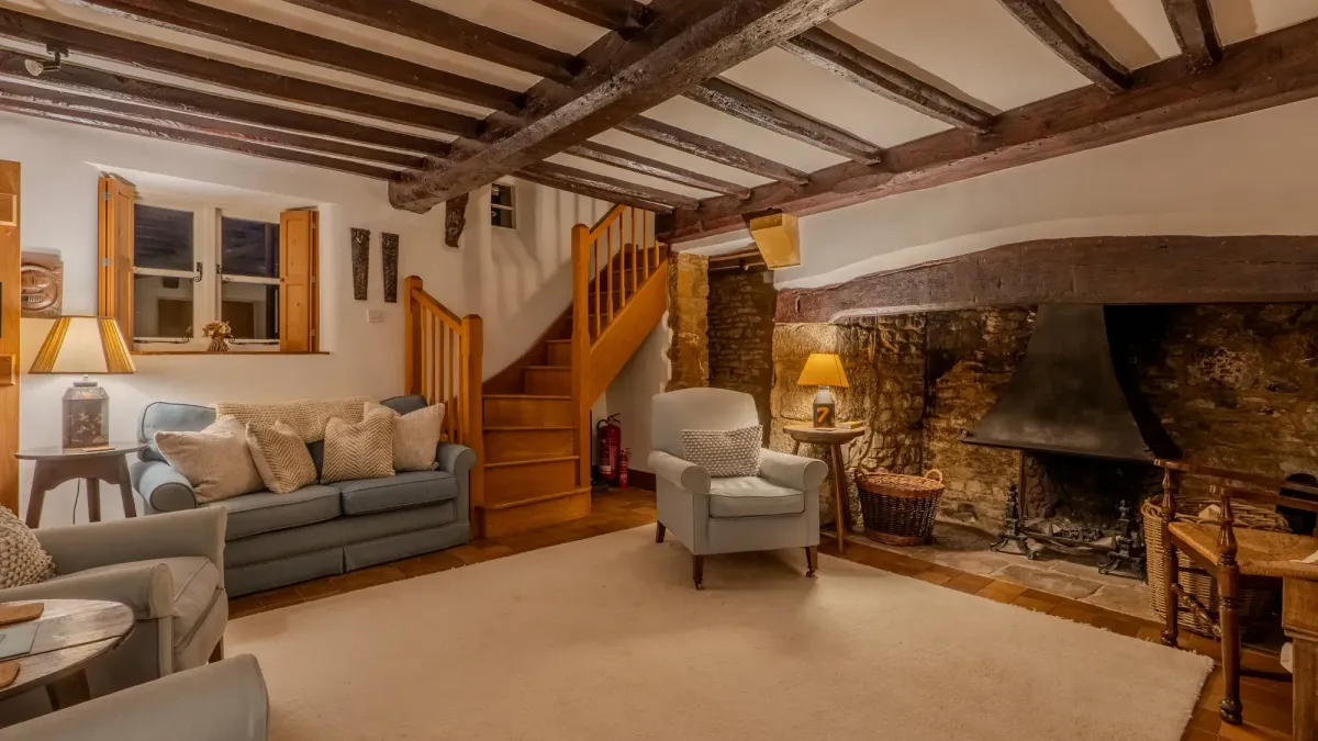 The living room at Well Cottage, with its stone inglenook fireplace, blue sofas and beamed ceiling