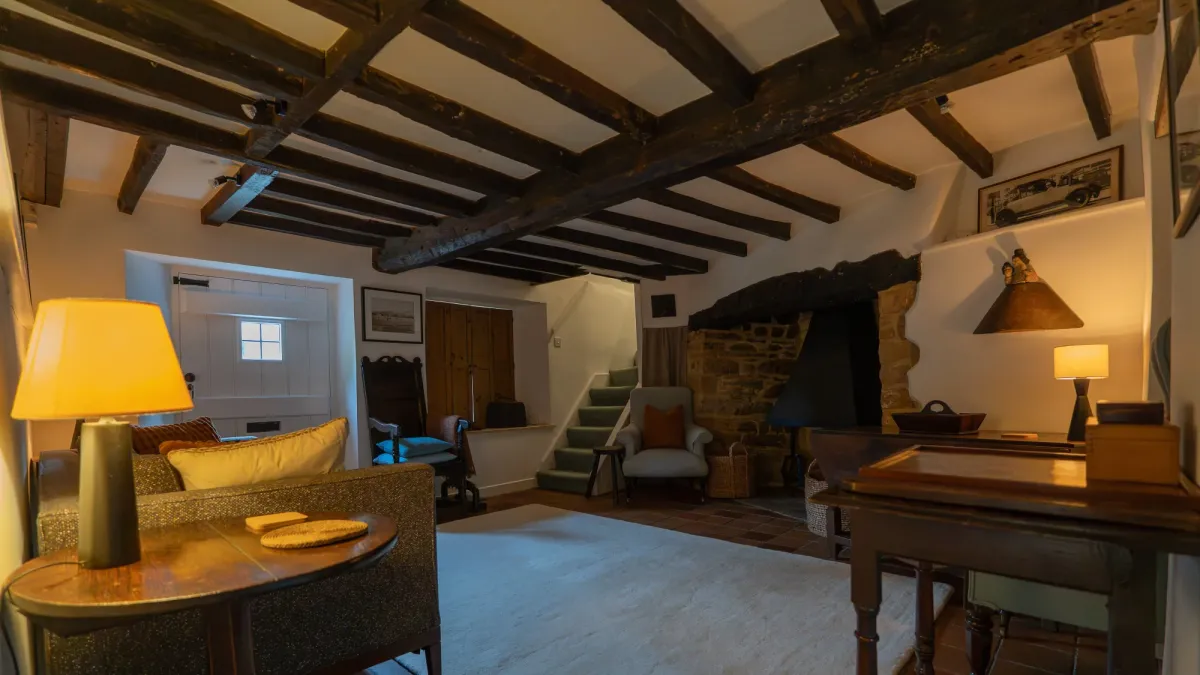 The snug at Well Cottage, lamp-lit in the evening, with its own stone inglenook fireplace