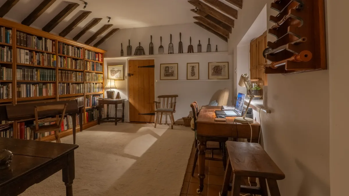The book-lined library at Well Cottage with a writing desk set into the window