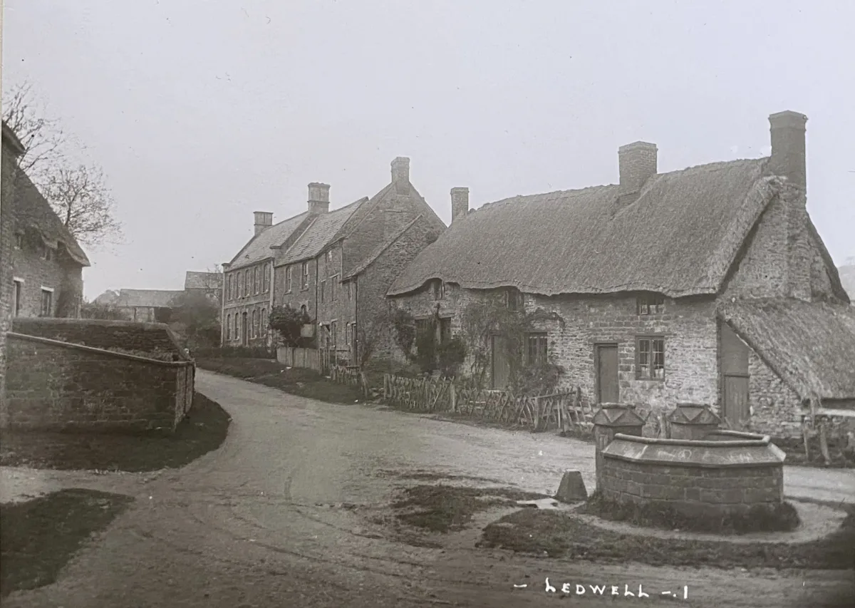 Early photograph of Ledwell village showing Well Cottage with its thatched roof and the stone well in the foreground