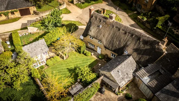 Aerial view over the thatched roof of Well Cottage and the quiet hamlet of Ledwell, Oxfordshire, in morning light