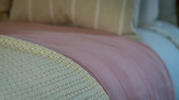 Soft pink and cream bed linen layered on the single bed