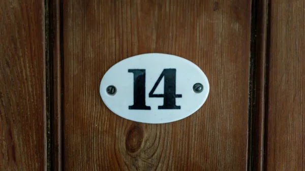 Enamel number plate reading 14 on an oak bedroom door