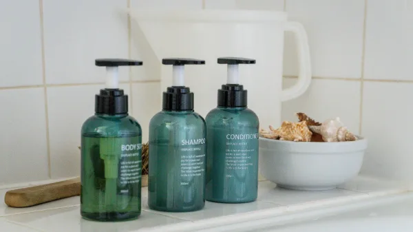 Shampoo, conditioner and body wash bottles beside a bowl of seashells on the bath ledge