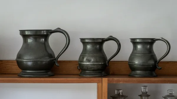 Three antique pewter tankards on the kitchen dresser shelf