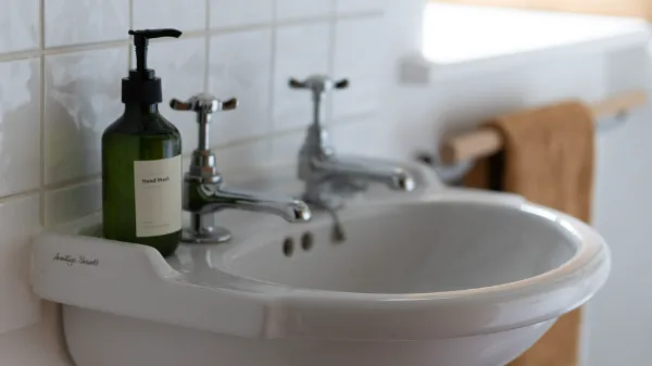 The upstairs basin with chrome taps, hand wash and a linen towel on a wooden rail