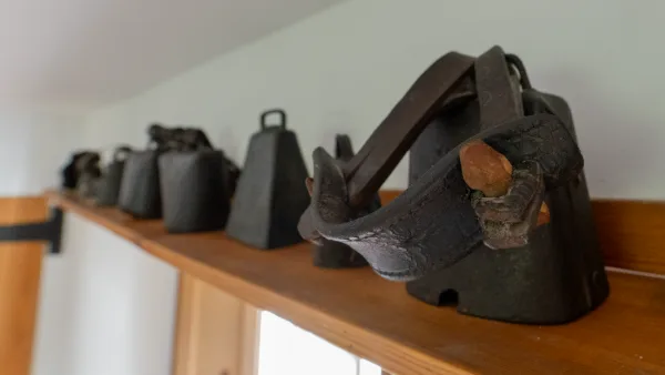 A row of antique cast-iron flat irons lined up on a high kitchen shelf