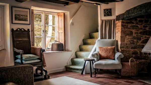 The snug hallway with an antique rocking chair, wingback armchair and the cottage staircase