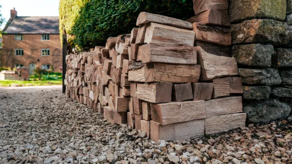 Stacked firewood logs along the stone wall, Ledwell cottages in the background