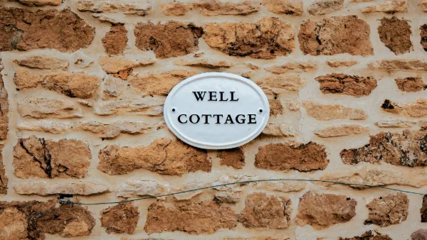 The Well Cottage name plaque on the honey-stone wall