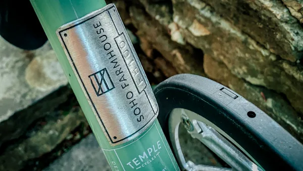 Close-up of the green bicycle head badge against the cottage stone wall