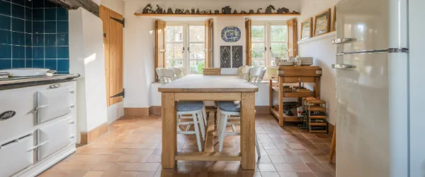 The kitchen from the doorway: Aga on the left, oak table in the centre, quarry tiles and beamed ceiling