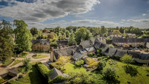 Aerial view of Ledwell's walled gardens, stone cottages and the thatched roof of Well Cottage in summer
