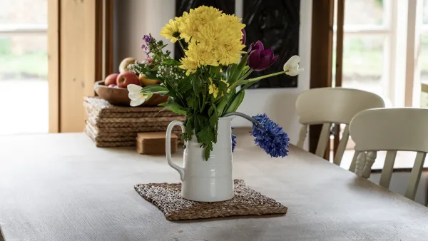 A jug of fresh garden flowers on the kitchen worktop, morning daylight through the cottage window behind