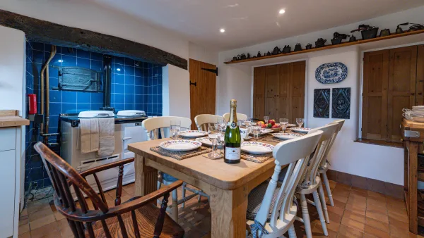 The kitchen table laid for supper in the evening, looking down to the Aga glowing in its blue recess