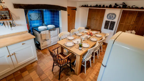 The oak farmhouse table in the kitchen laid for breakfast, with the Aga glowing in the background