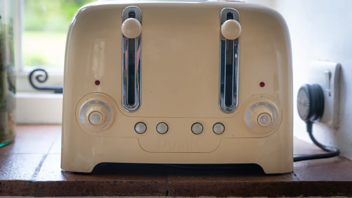 A cream four-slice Dualit toaster on the terracotta sill by the window, its chrome levers and dials catching the garden light