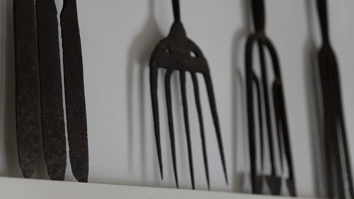 A close detail of the row of antique iron hay forks mounted along the high shelf above the library doorway