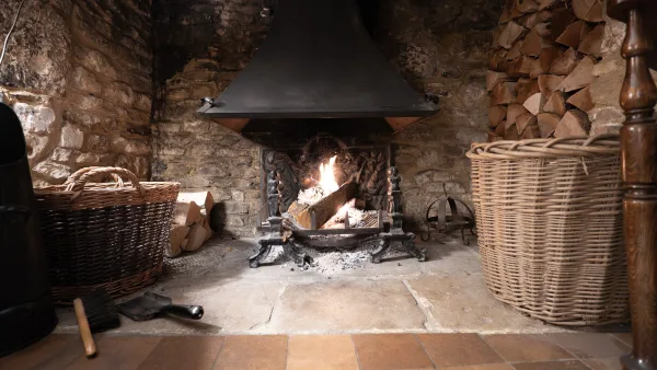 The beamed living room at Well Cottage with armchairs, books and an inglenook fireplace