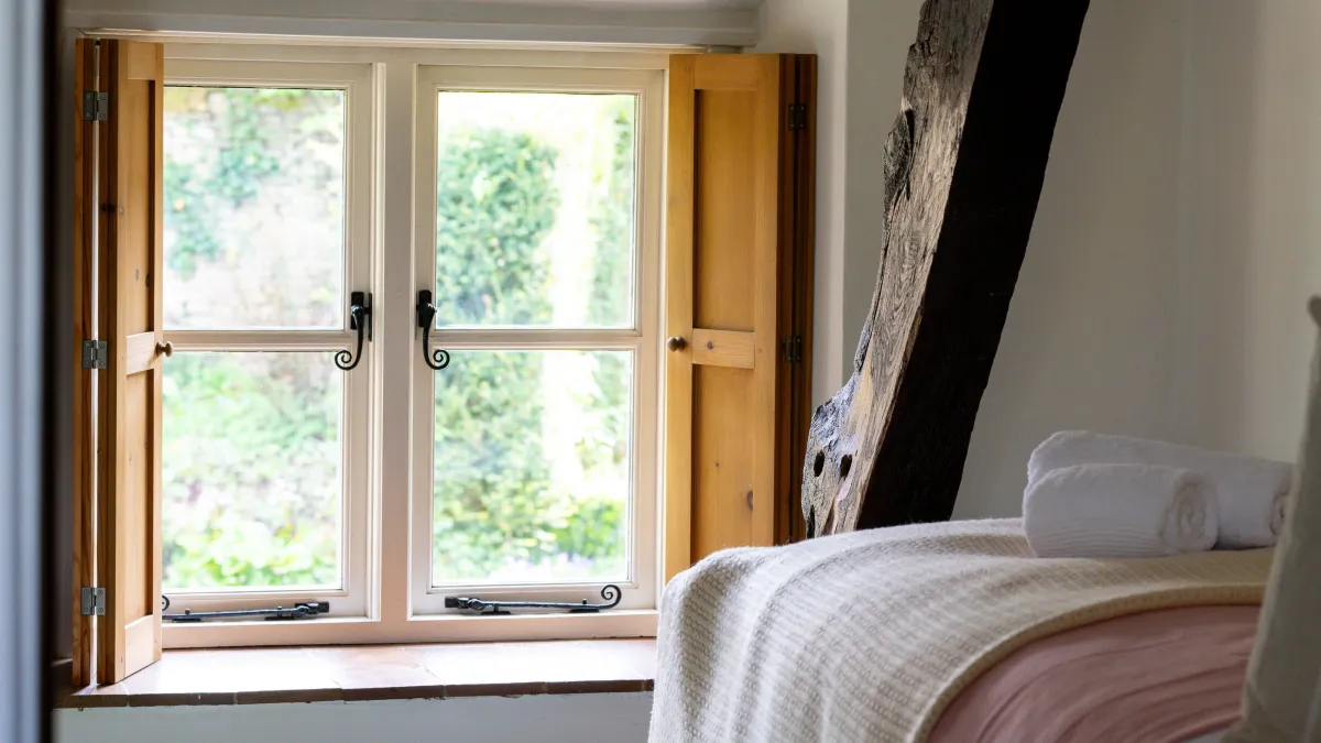 Single bedroom at Well Cottage, pine shutters open onto the garden