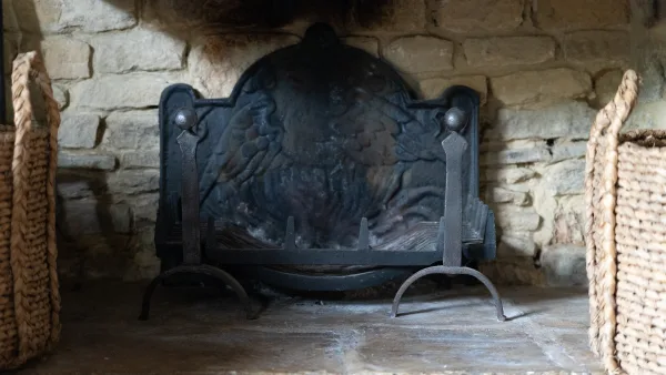 The inglenook fireplace in the snug at Well Cottage, logs stacked to one side and the fire lit against a dark evening