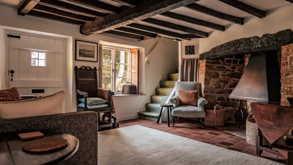 The snug at Well Cottage with exposed stone and a winding cottage staircase
