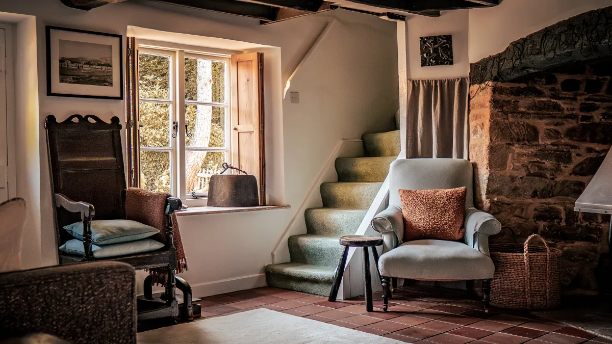 The good armchair in the snug pulled up beside the carpeted winding staircase and a wall of bare Cotswold stone, lit by the deep cottage window