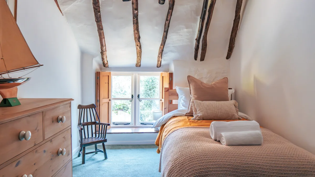 The exposed oak beams of the Twin Room running across the sloping plastered ceiling above the window and dresser