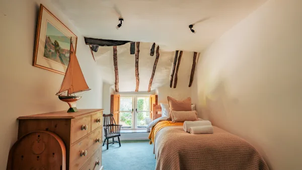 The pine dresser in the Twin Room at Well Cottage, a model sailboat on top and dark oak beams overhead