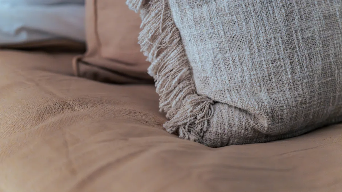 A detail of the soft ochre linen and a fringed oatmeal cushion on one of the single beds